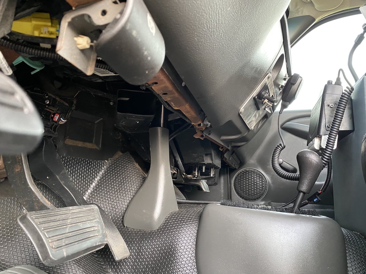 A close-up view
of the bottom edge of a truck dashboard. Barely visible along the bottom
edge is some cable and wiring which has been dressed with nylon zip ties.
In the background is visible an amateur radio transceiver mounted to the
front of a center console and some aftermarket lighting controls mounted to
the dashboard.