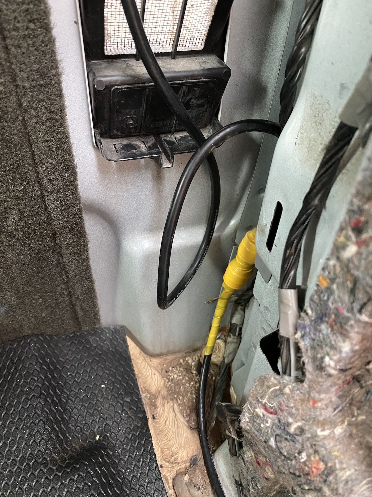 A close-up view
of some coaxial cable coming down from above into a connection wrapped in
yellow vinyl tape. The cable continues along the floor toward the viewer. In
the background are visible the inside of a truck body, some insulation, and
an air vent.